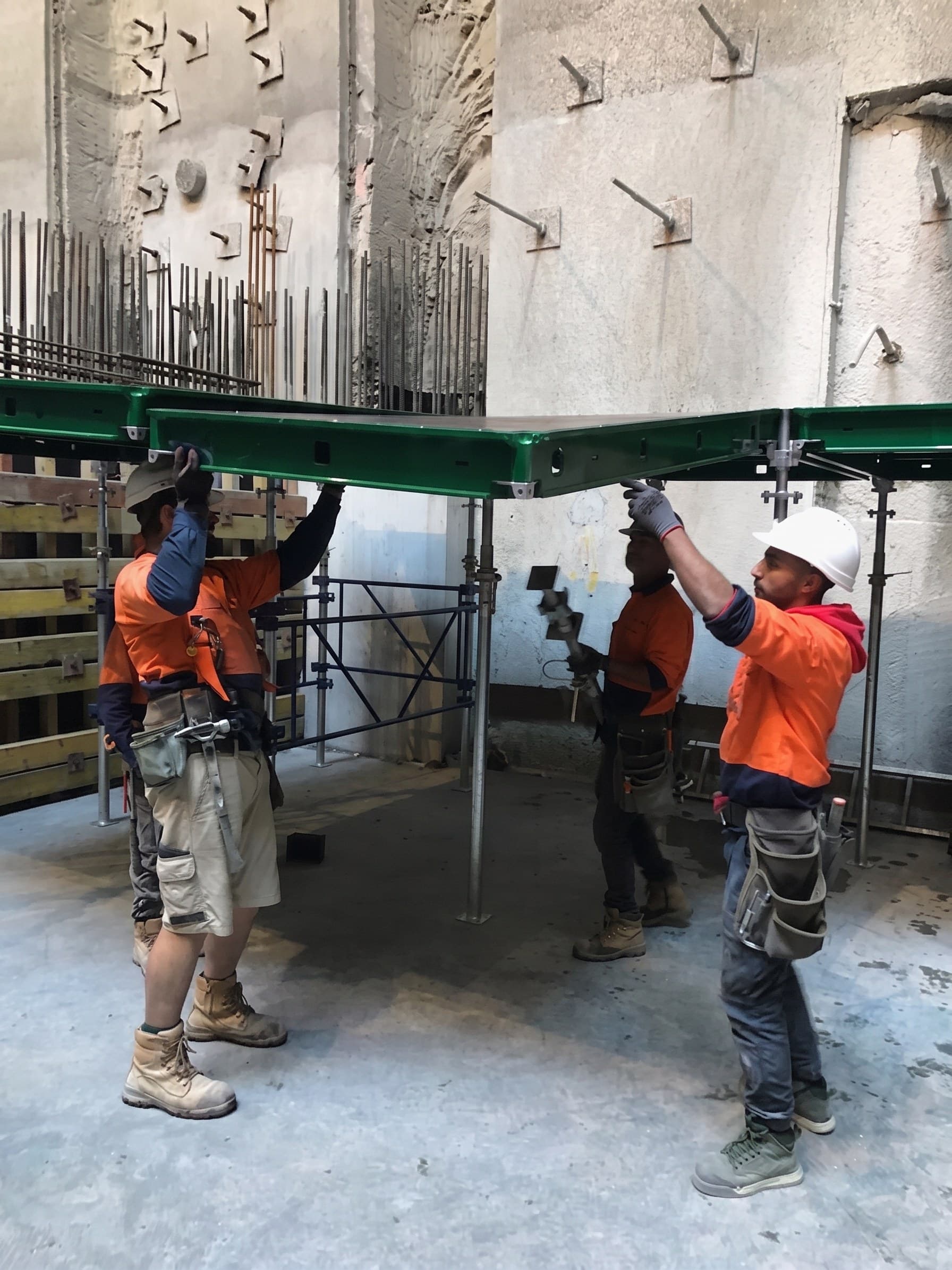 A crew setting a beam under an Early Strip deck, the panels bearing on fork heads above